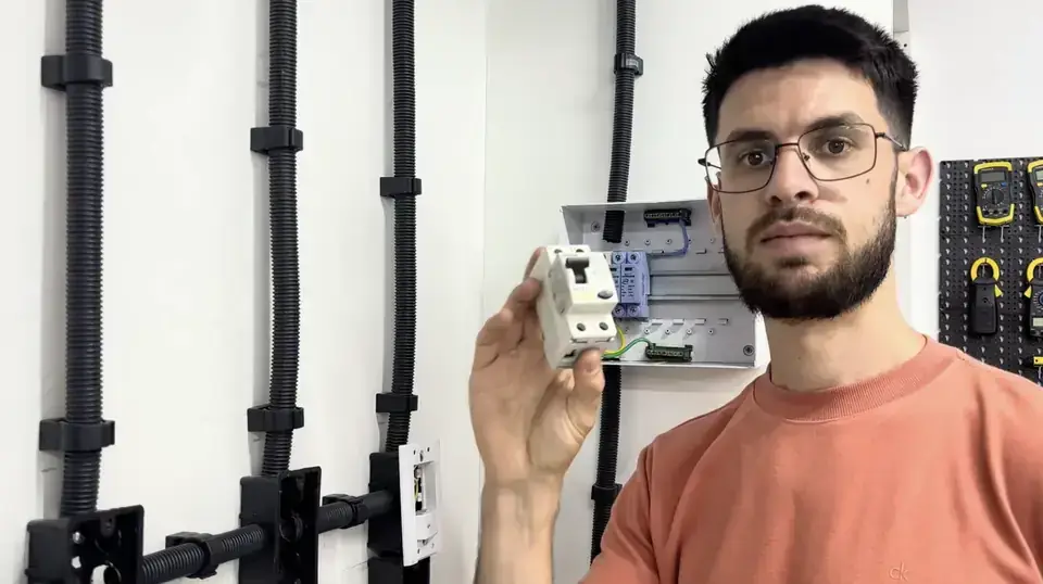 Instrutor apresentando um disjuntor em painel elétrico didático