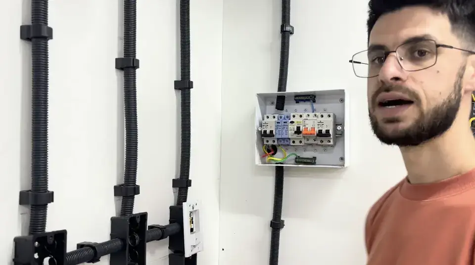 Instrutor ao lado de um quadro de distribuição residencial